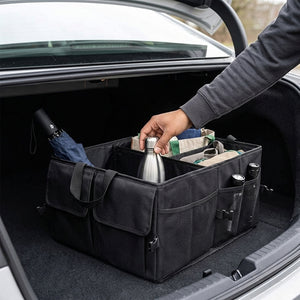 Person organizing items in a black car trunk organizer.
