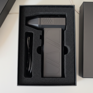 Black electronic device with a cable in a black foam-lined box on a light surface.