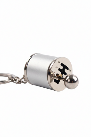 Metal keychain with cylindrical design and puzzle piece cutout on a white background