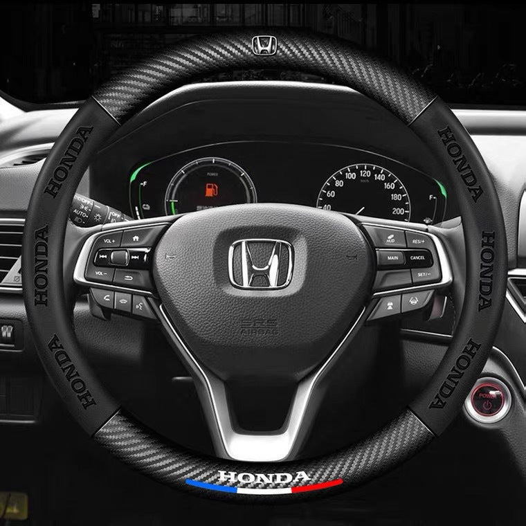 Steering wheel with Honda logo and carbon fiber texture in a car interior.