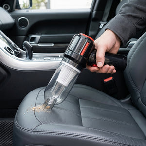 Person cleaning car interior with a handheld vacuum cleaner.
