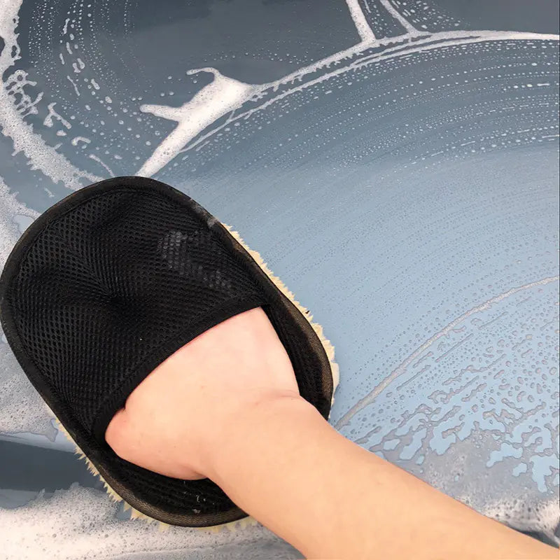 Person wearing a black slipper on a car's windshield with soapy water.